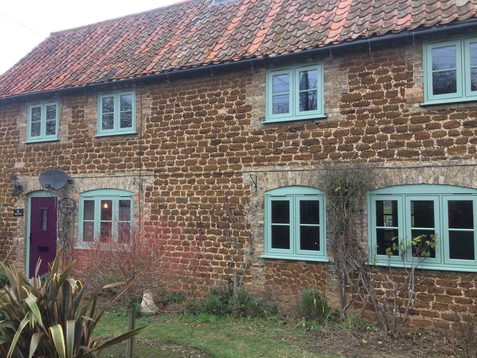 Front view of a house with chartwell green windows and a purple front door